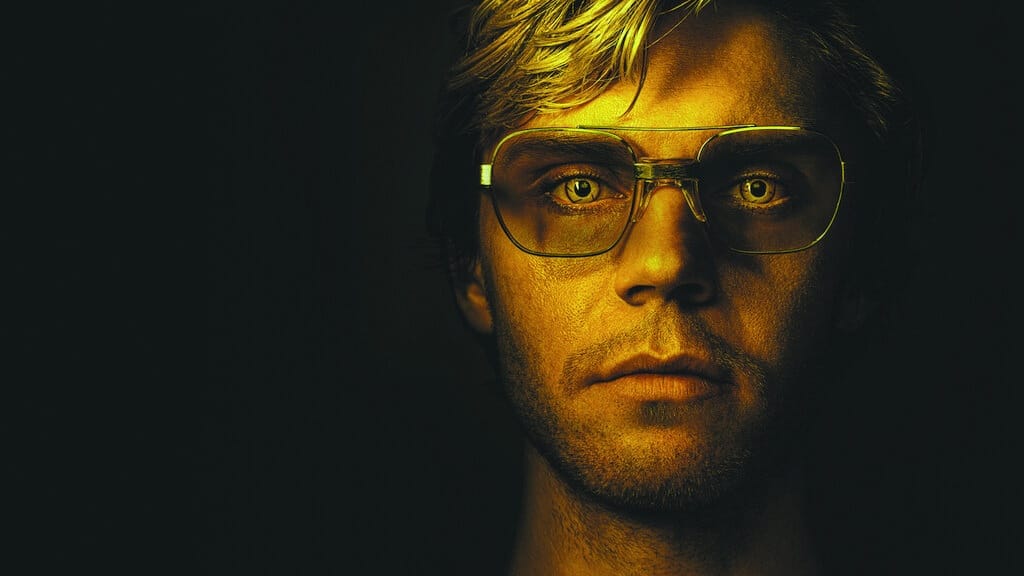 Intense portrait of Evan Peters as Jeffrey Dahmer in yellow-tinted aviator glasses.