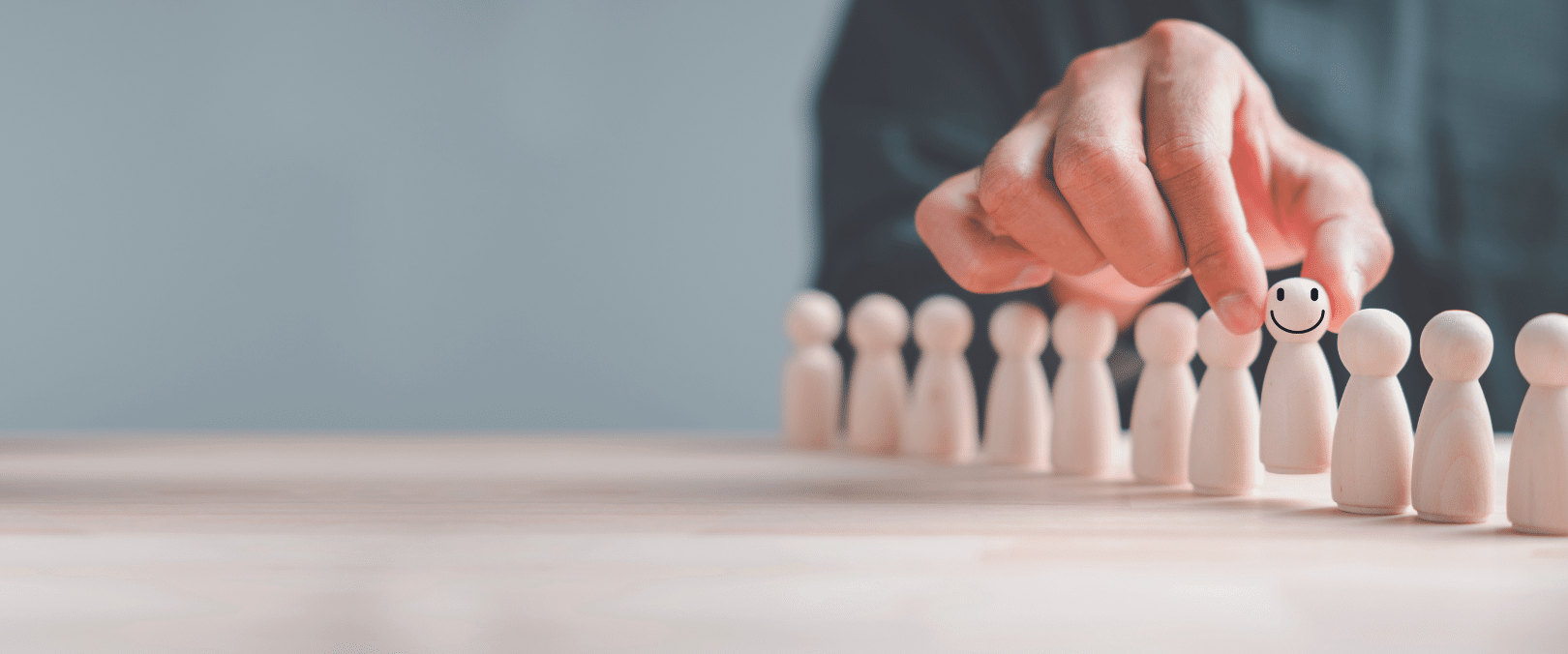 Image representing eye-care recruitment: lose-up photograph of a row of "meeple" game pieces; a hand has selected one piece and a smiley face is super-imosed over that piece.