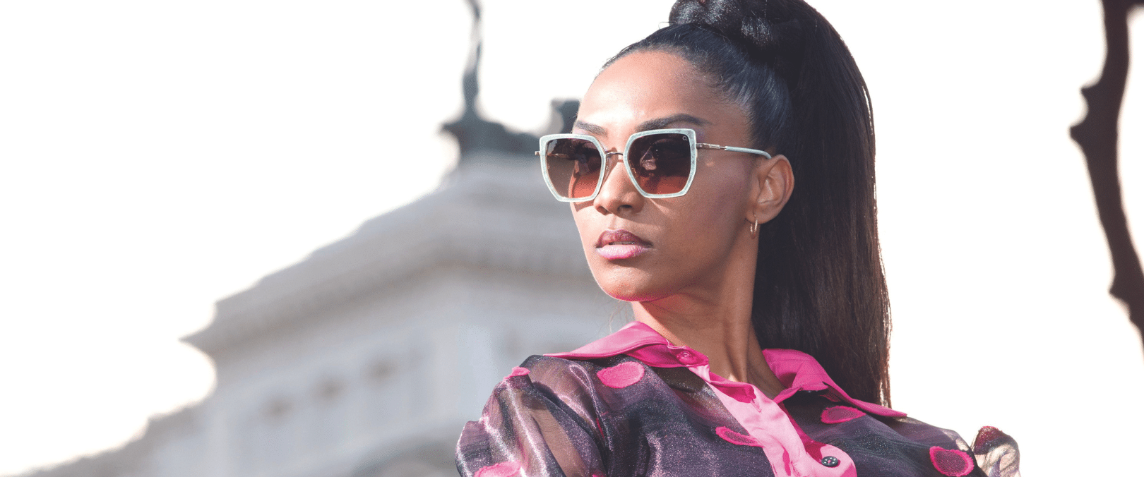 Model showcasing contemporary sunglasses with a blurred building in the background