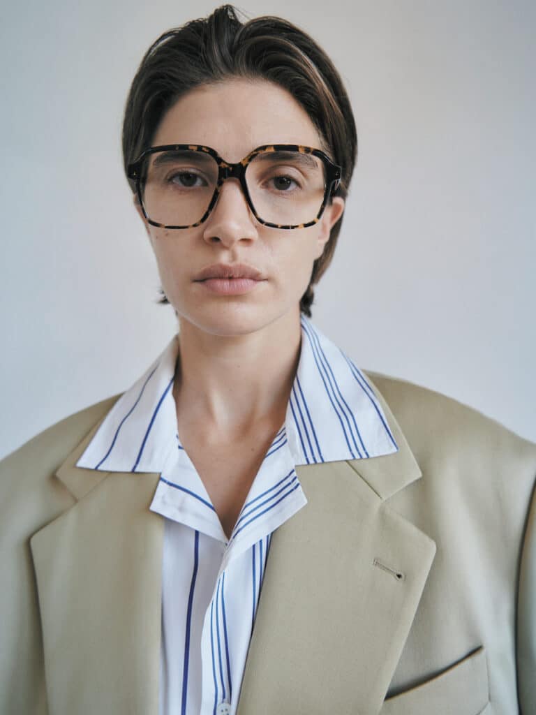Fashion-forward woman in a smart beige suit and blue-striped shirt, showcasing GIGI STUDIOS' bold patterned eyewear
