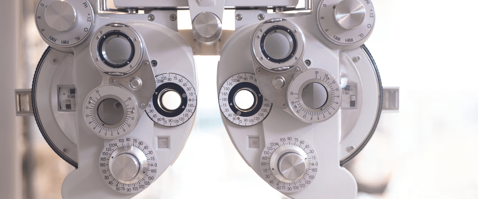 Close-up of a phoropter, a piece of optometry technology used for eye testing, showing numerous lenses and dials for vision correction assessment.