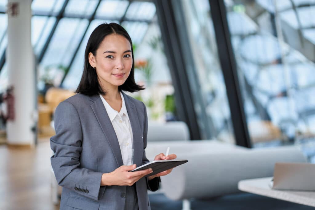 Smiling businesswoman holding digital tablet standing in office.