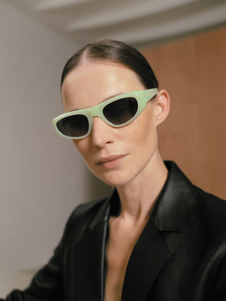Woman in a black jacket wearing pastel green Spanish eyewear (KALEOS sunglasses).