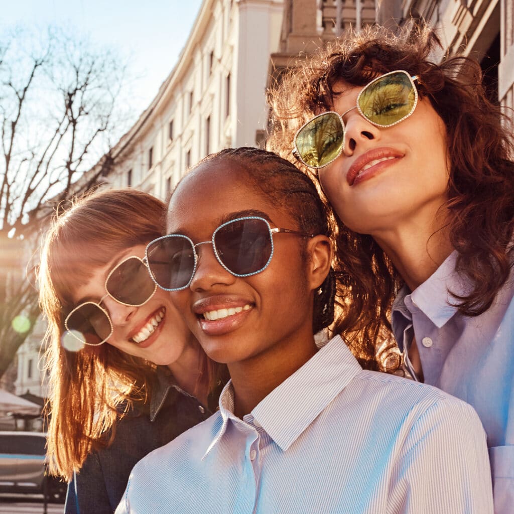 Three young ladies wearing stylish sunglasses.